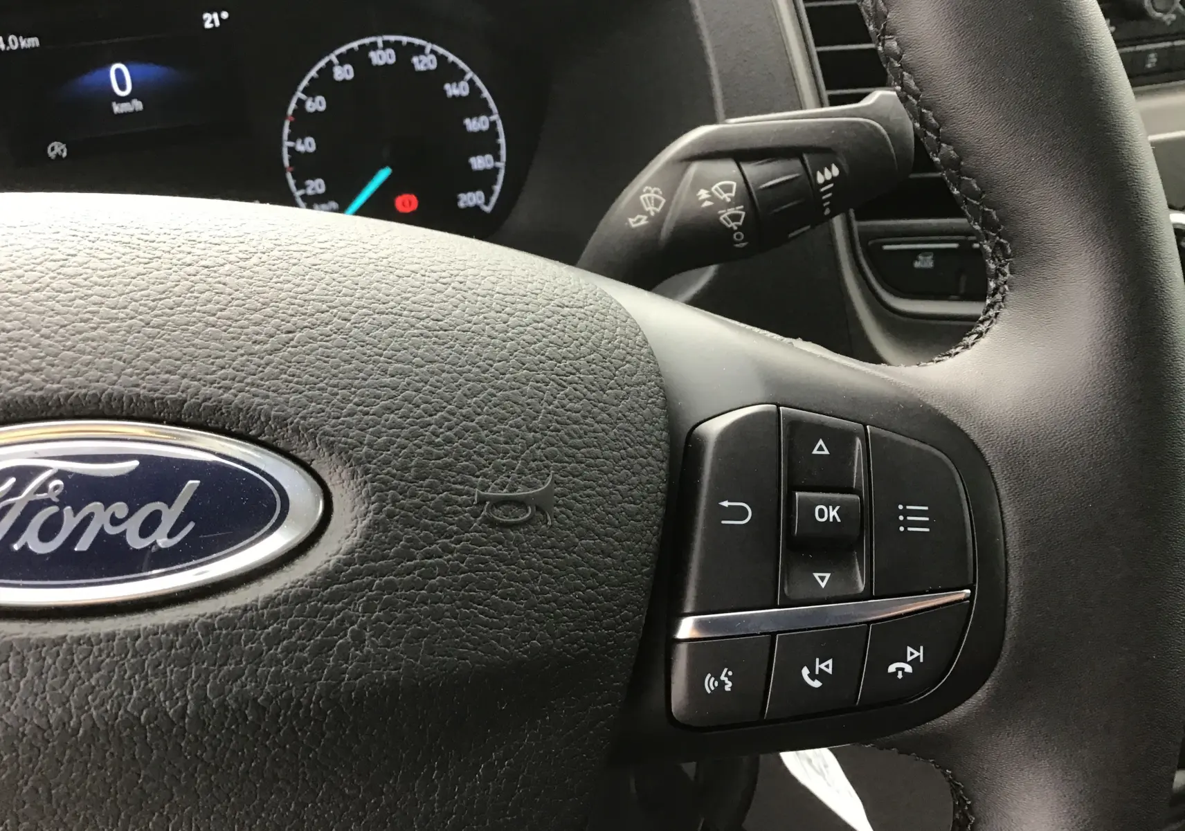 Gros plan sur le volant en cuir noir du Ford Transit Chassis Cabine 2024 avec commandes multifonctions intégrées.