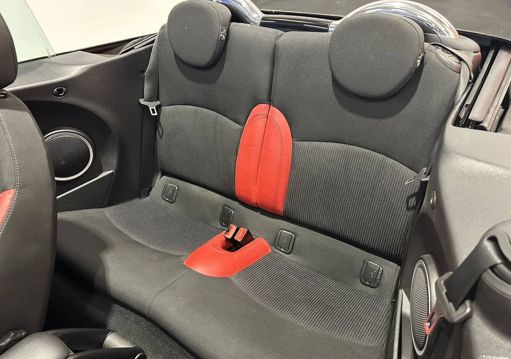 Vue rapprochée des sièges arrière noirs avec inserts rouges du MINI Cabriolet Cooper S rouge de 2012.
