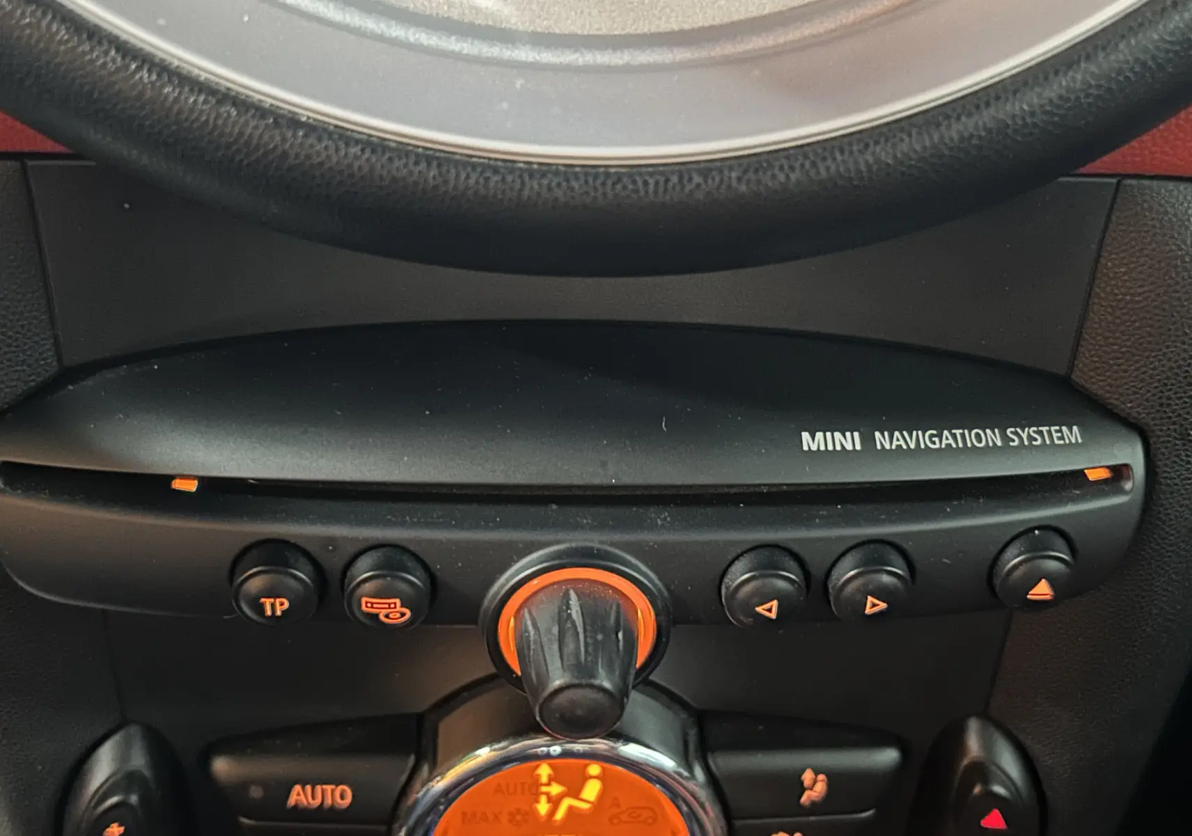 Gros plan sur la console centrale noire du MINI Cabriolet rouge, mettant en valeur le système de navigation et les commandes climatiques.