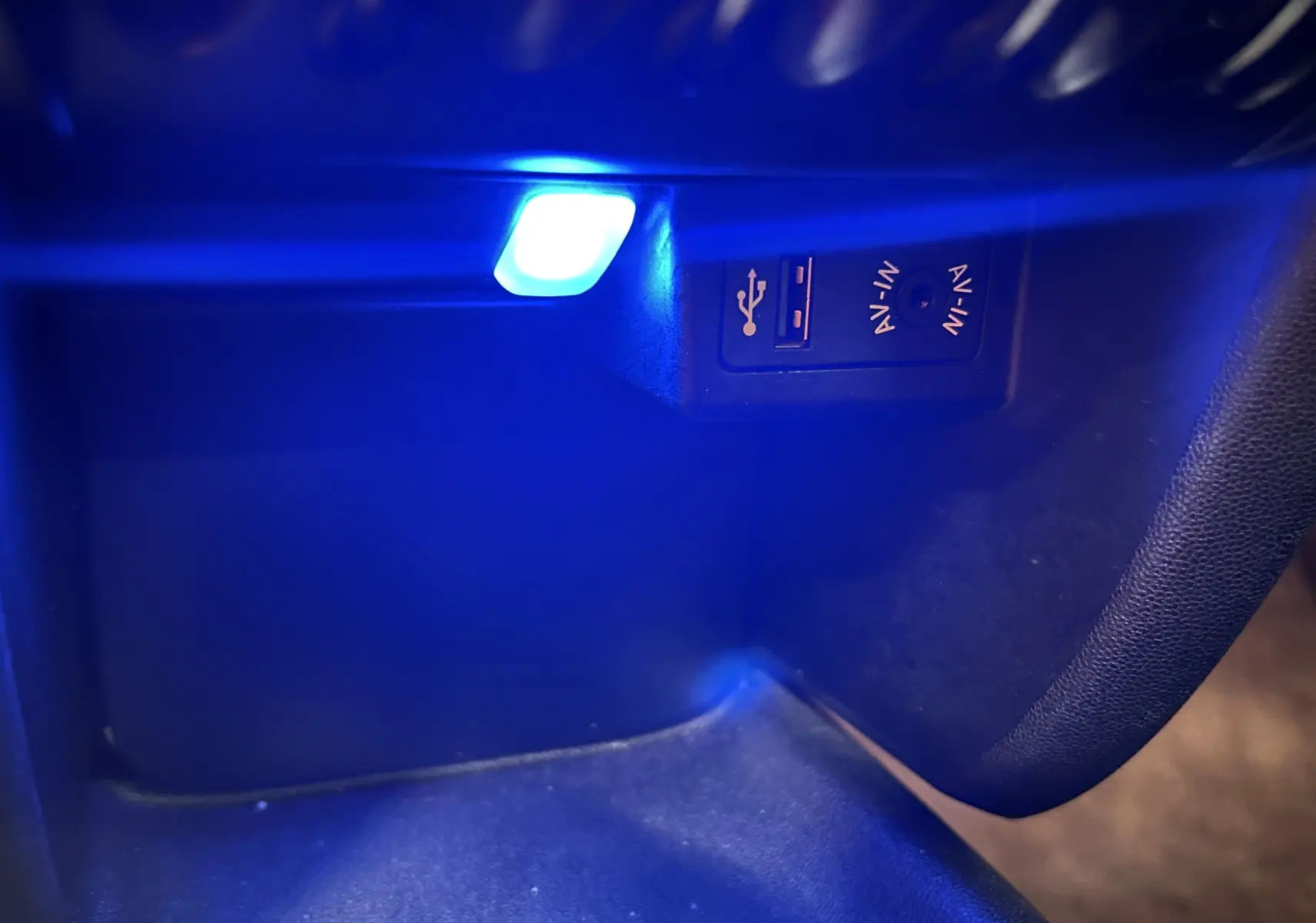 Prise USB et entrée AV-IN éclairées en bleu dans le coffre à gants d'une MINI Cabriolet rouge 2012.