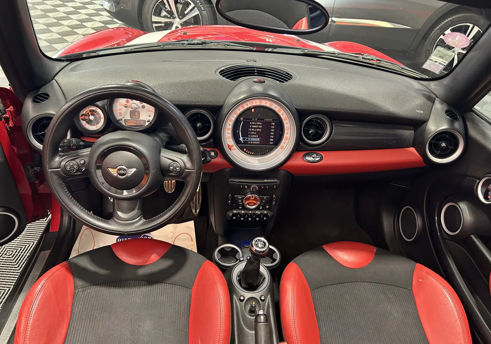 Gros plan sur la plaque de seuil de porte MINI Cooper S rouge, mettant en valeur le logo et l'intérieur noir.