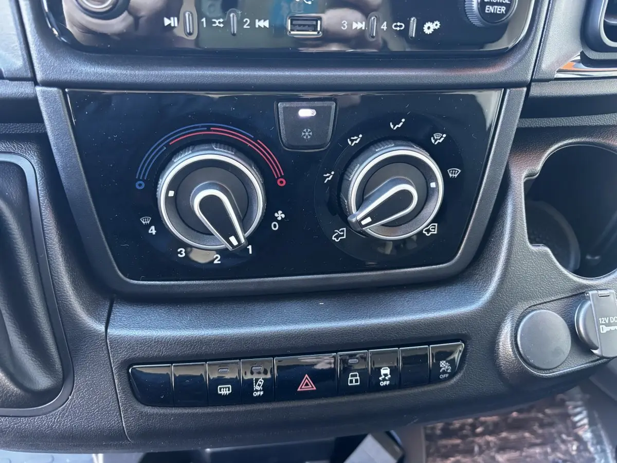 Gros plan sur les commandes de climatisation et les boutons de sécurité du tableau de bord du Peugeot Boxer Fourgon blanc.