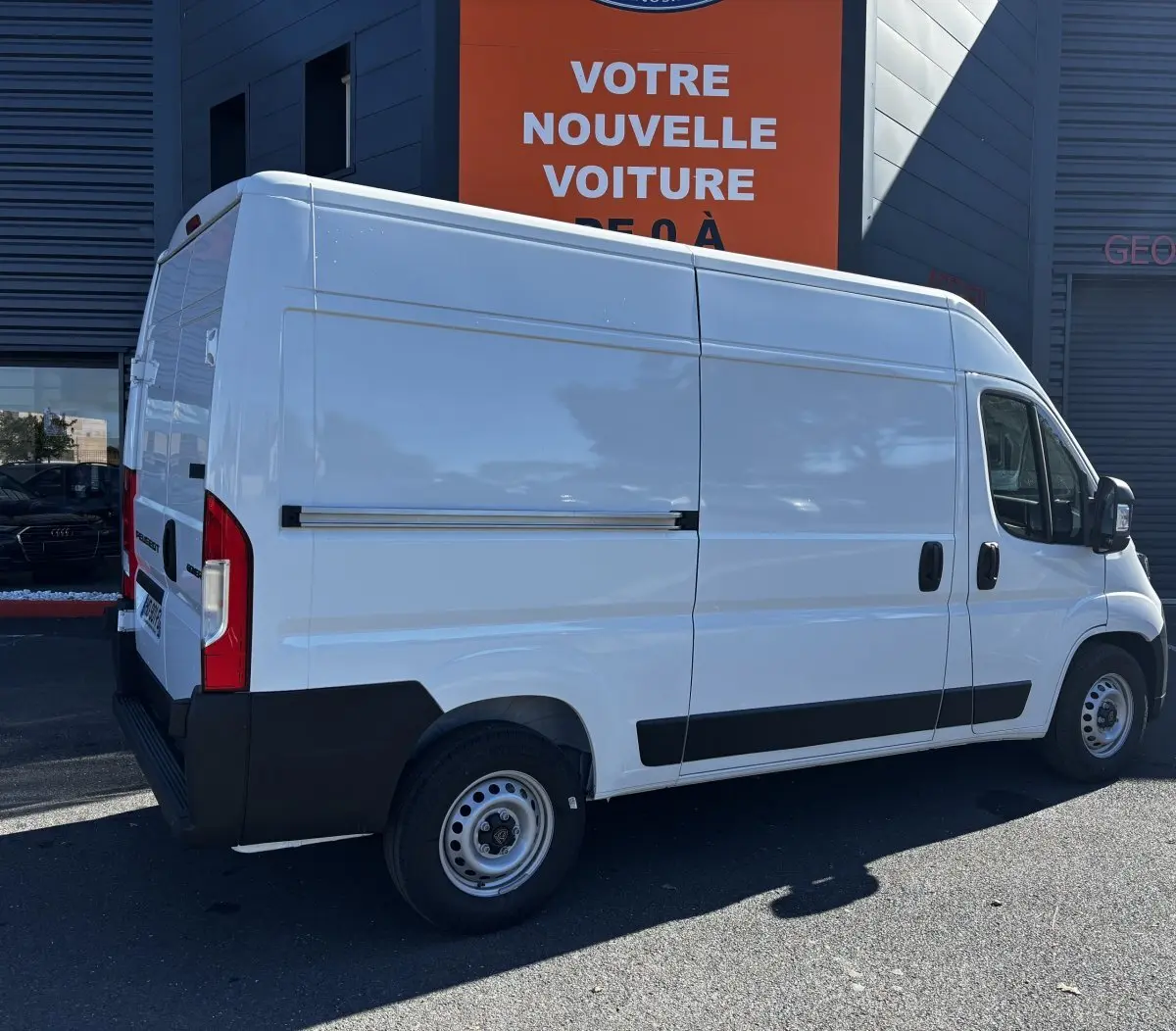 Vue 3/4 arrière droite d'un Peugeot Boxer Fourgon blanc avec carrosserie haute et bas de caisse noir.