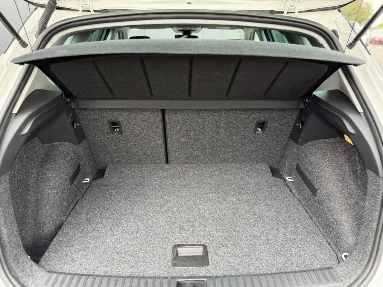 Coffre ouvert vu de l'arrière d'un SEAT Arona blanc, montrant l'espace de rangement et la couverture de coffre.