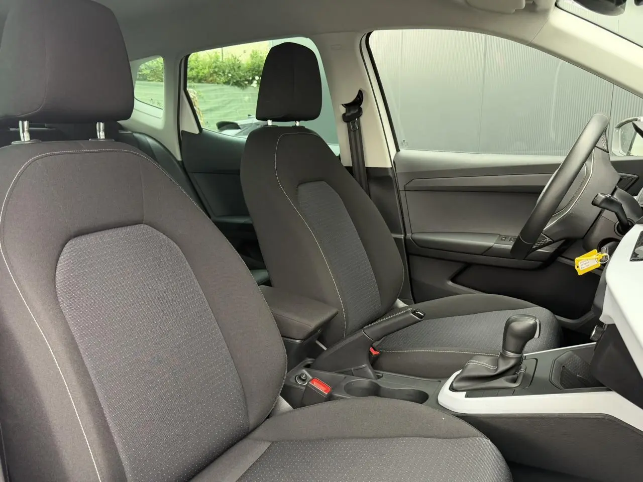 Vue intérieure côté droit du SEAT Arona 2025, sièges tissu gris et console centrale avec boîte automatique.