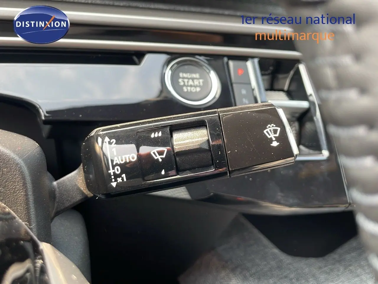 Gros plan sur la commande d’essuie-glace et le bouton start/stop du tableau de bord d’un Peugeot 3008 gris Artense 2025.