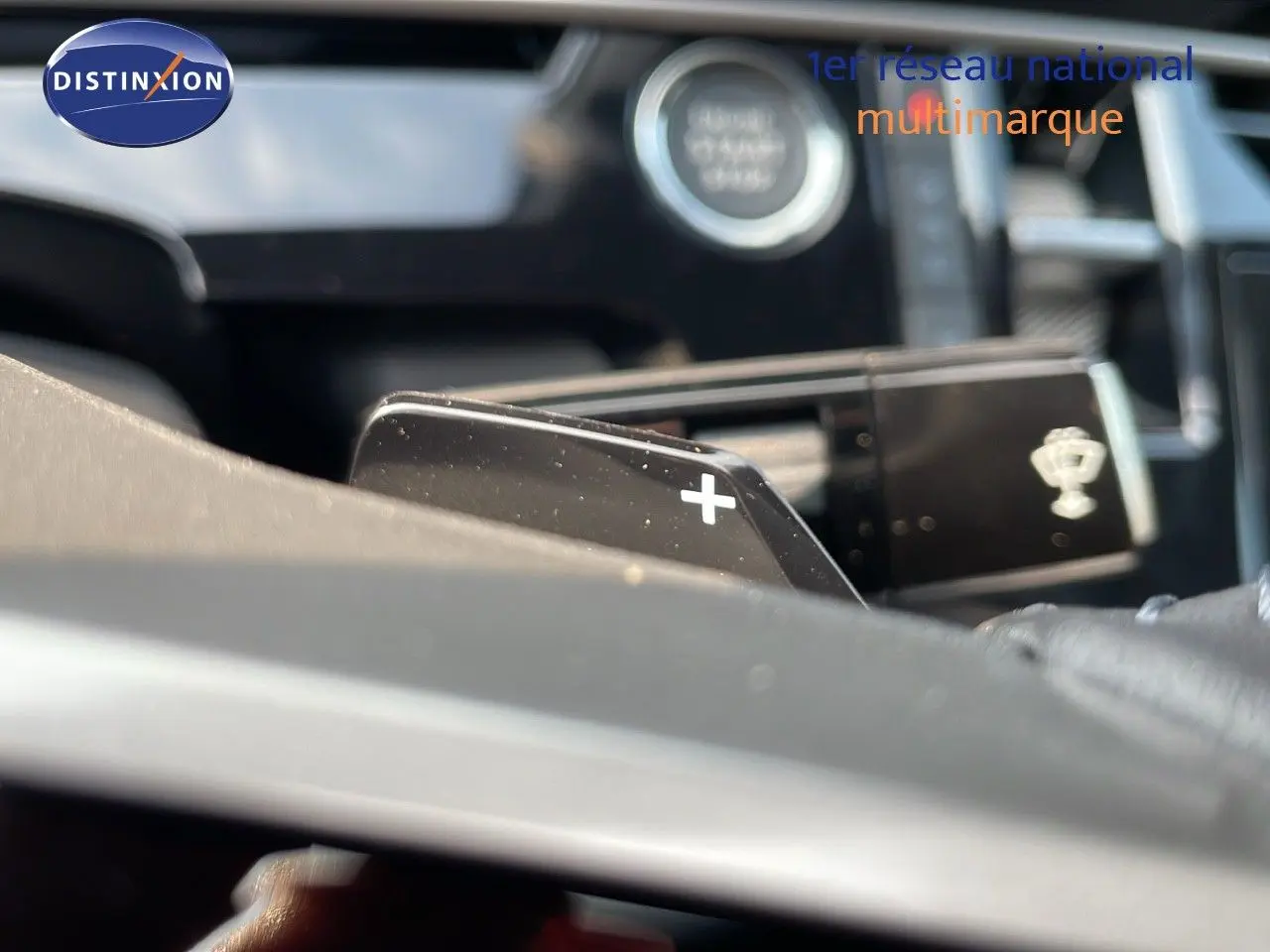 Gros plan sur la palette de changement de vitesse + au volant d’un Peugeot 3008 gris Artense, intérieur moderne et lumineux.