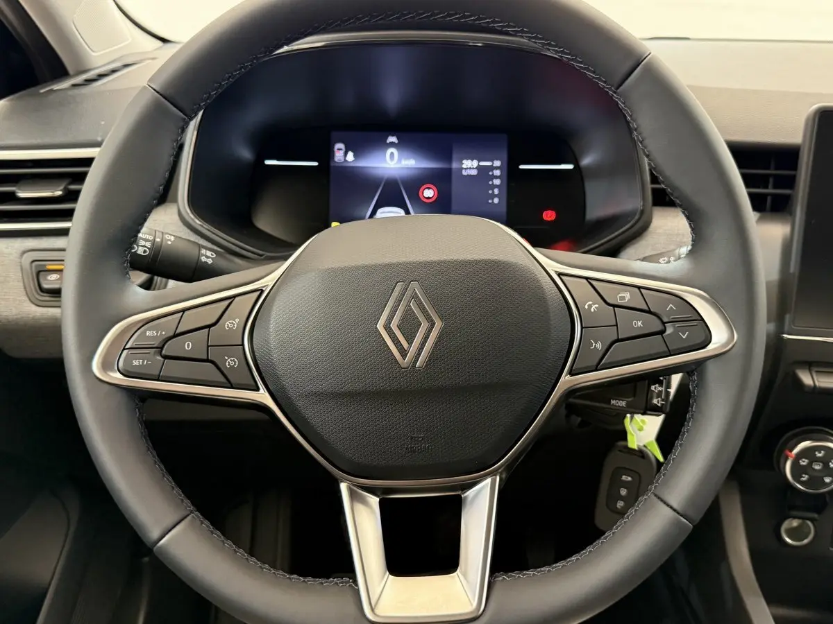 Vue rapprochée du volant cuir noir de la Renault Clio 2025 avec commandes multifonctions et tableau de bord numérique.