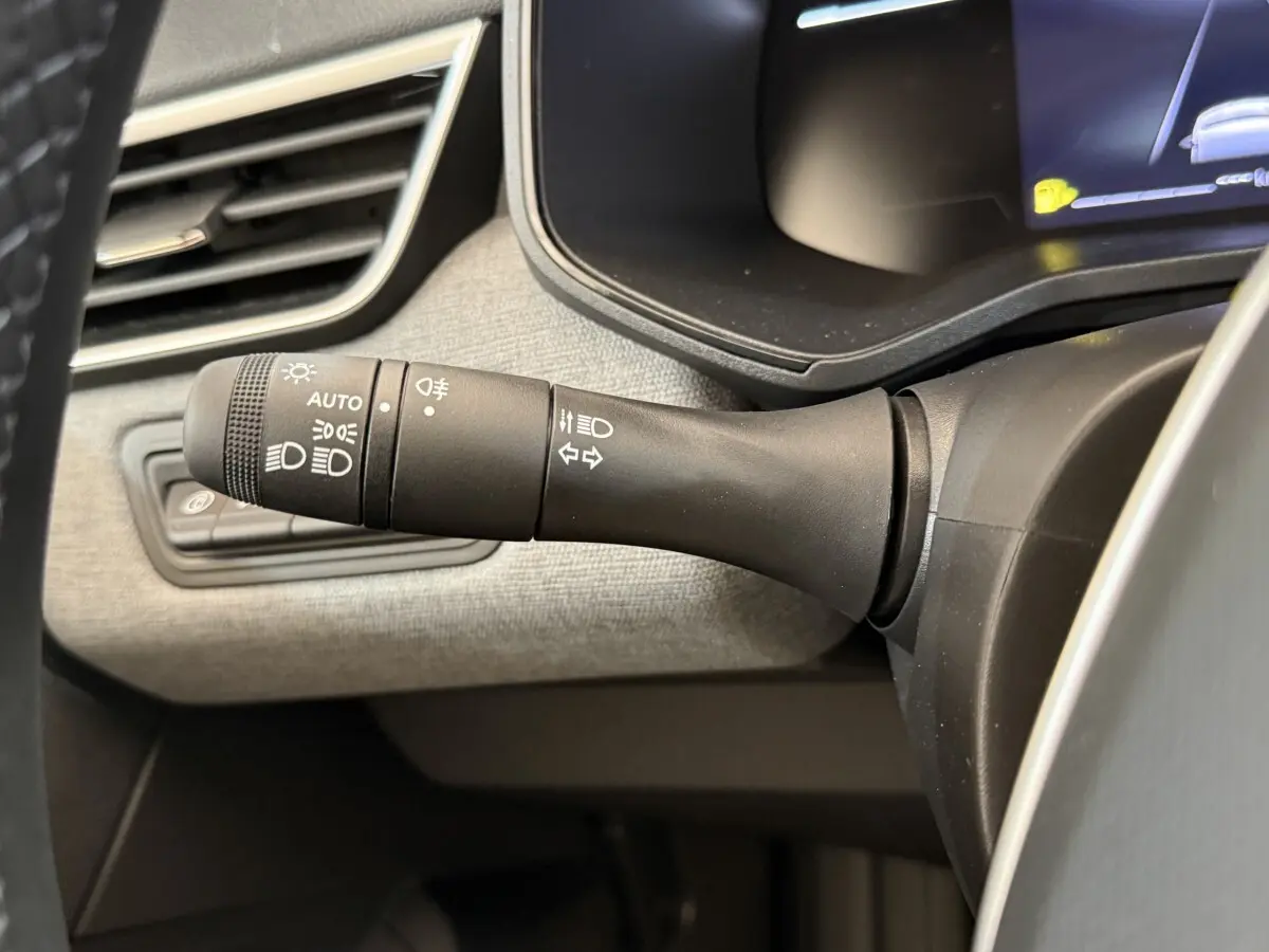 Gros plan sur la commande des phares et clignotants à gauche du volant dans l'habitacle d'une Renault Clio noire 2025.