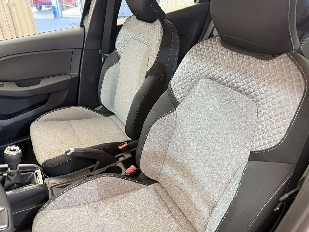 Intérieur de la Renault Clio Evolution Blue dCi 100 2025, vue côté droit sur les sièges avant gris clair avec surpiqûres.