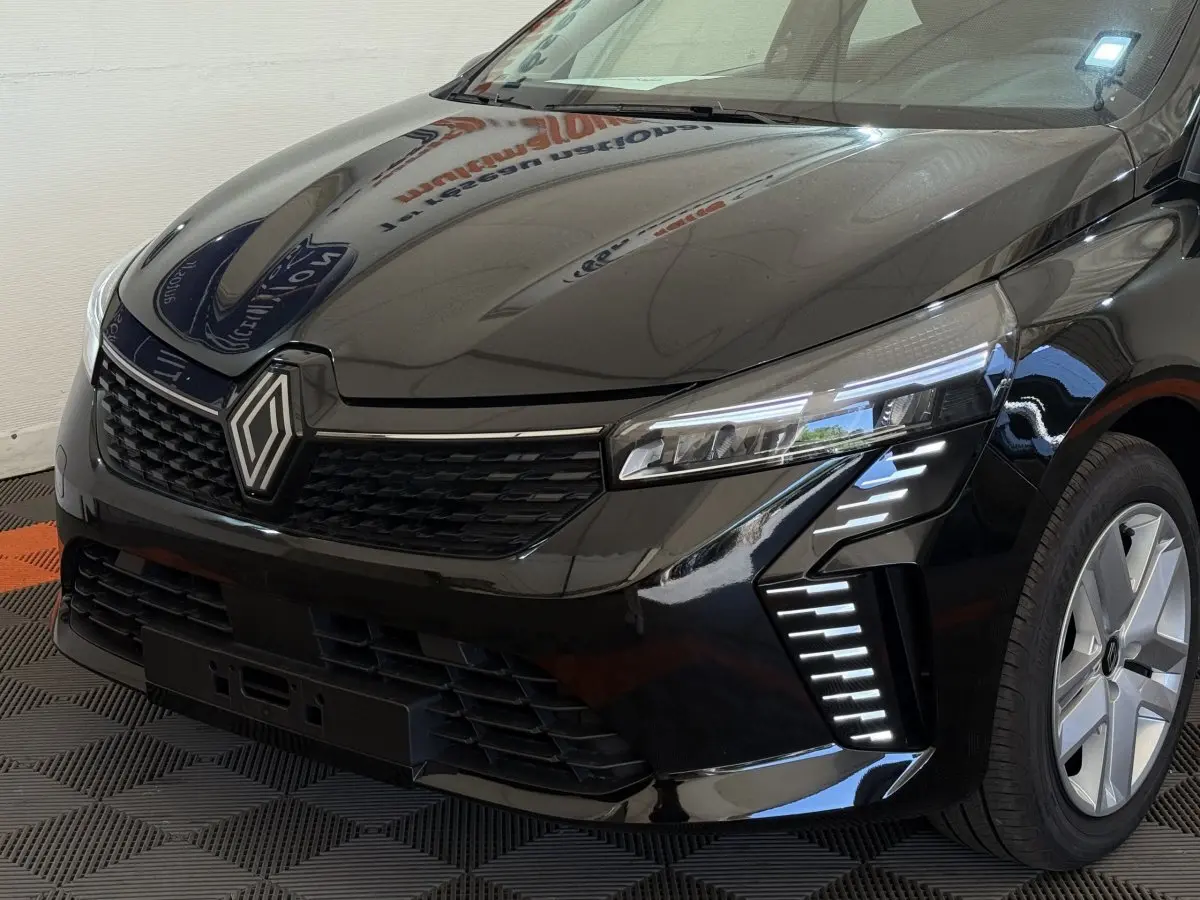 Vue 3/4 avant droit d'une Renault Clio noire 2025 avec phares LED et calandre au logo Renault proéminent.