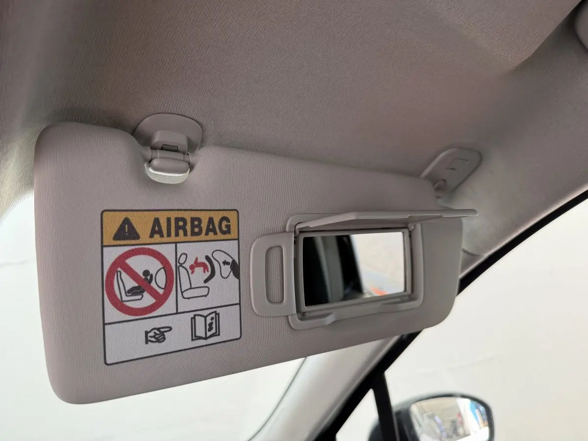 Détail du pare-soleil côté conducteur avec miroir ouvert et avertissement airbag dans une Renault Clio noire 2025.