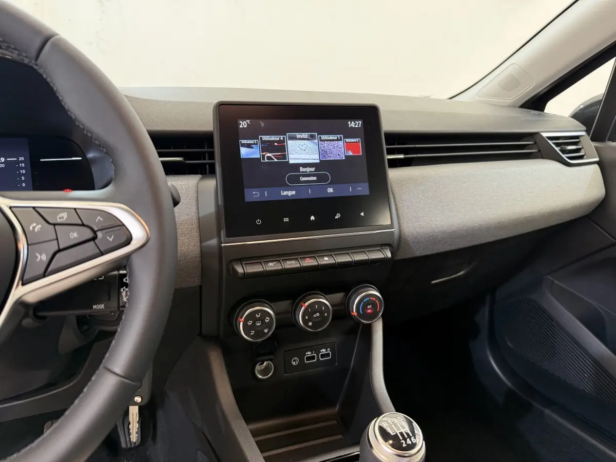 Vue intérieure de face du tableau de bord et console centrale de la Renault Clio noire avec écran tactile et volant multifonctions.