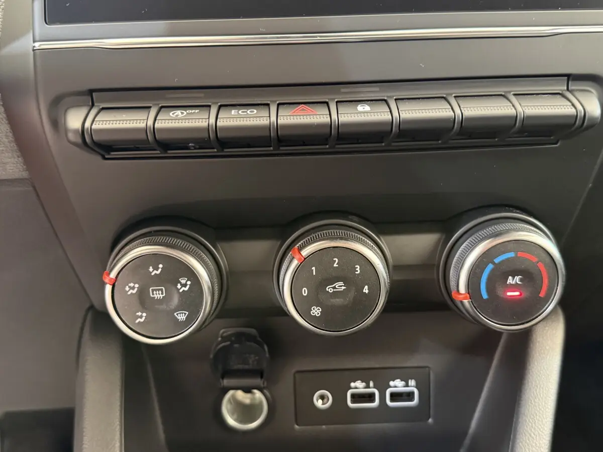Gros plan sur les commandes de climatisation et les ports USB du tableau de bord de la Renault Clio noire 2025.