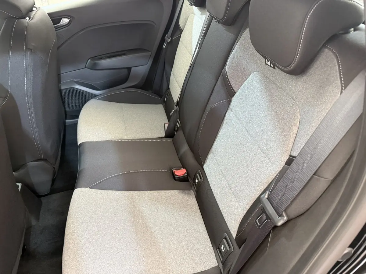 Vue intérieure côté arrière droit montrant la banquette bicolore gris clair et noir de la Renault Clio Evolution 2025.