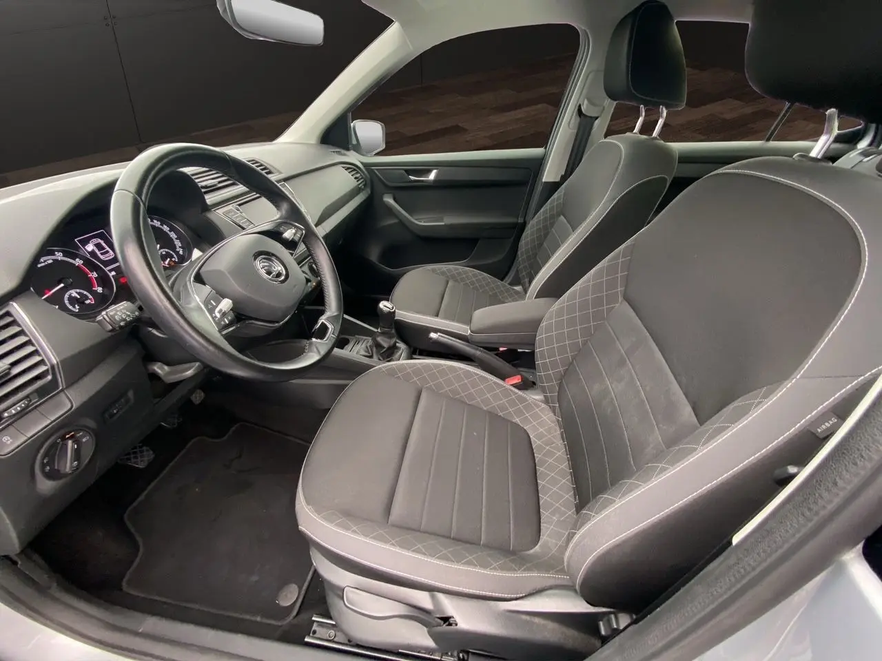 Vue intérieure côté conducteur de la Skoda Fabia gris argent 2021 avec sièges tissu noir et volant multifonction.