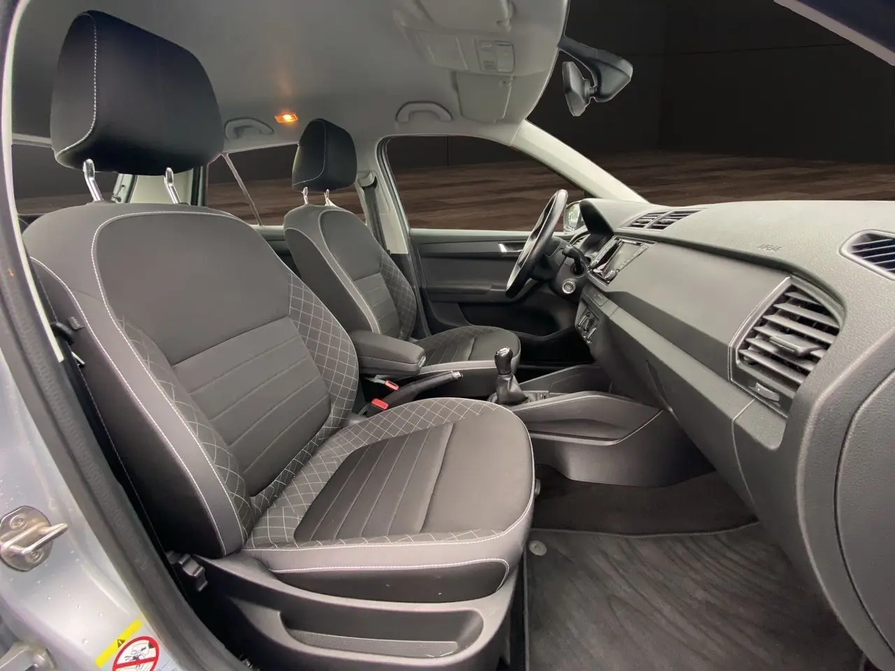 Vue intérieure côté droit de la Skoda Fabia 2021 gris argent, montrant les sièges avant et la console centrale avec boîte manuelle.
