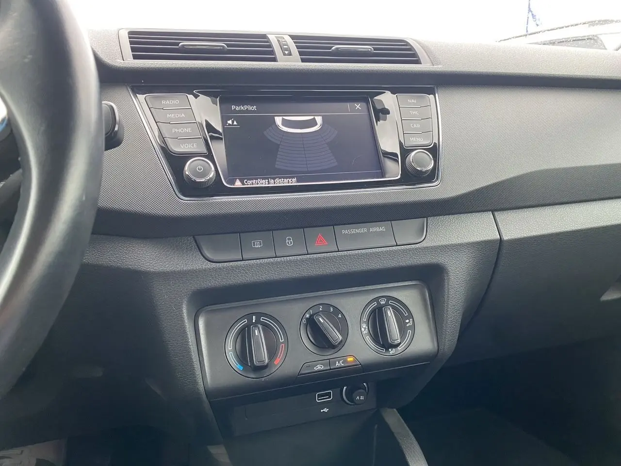 Vue intérieure centrée sur la console centrale d'une Skoda Fabia gris argent avec écran multifonction et commandes de climatisation manuelle.