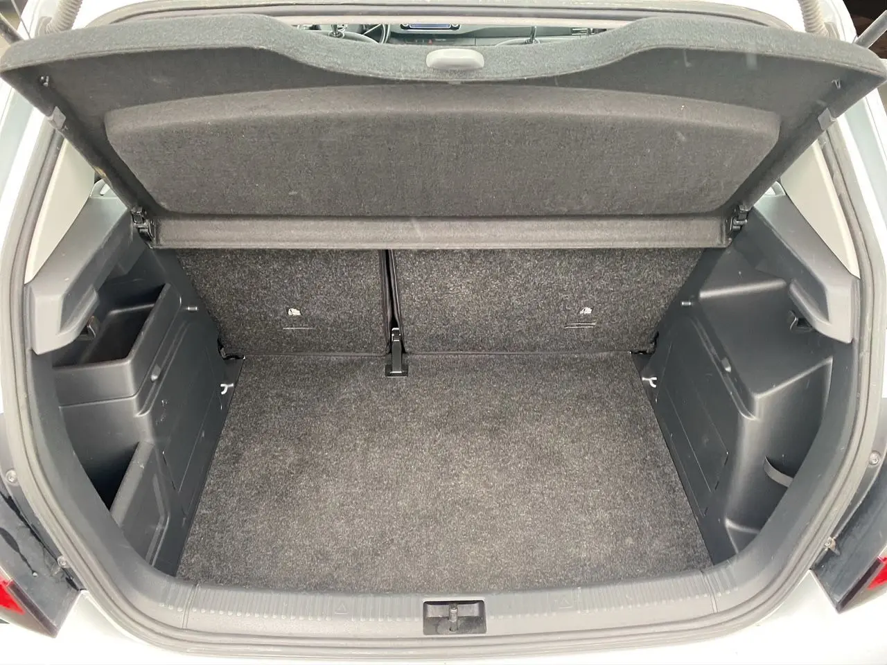 Coffre ouvert vu de l'arrière d'une Skoda Fabia gris argent, montrant l'espace de chargement et la tablette cache-bagages.
