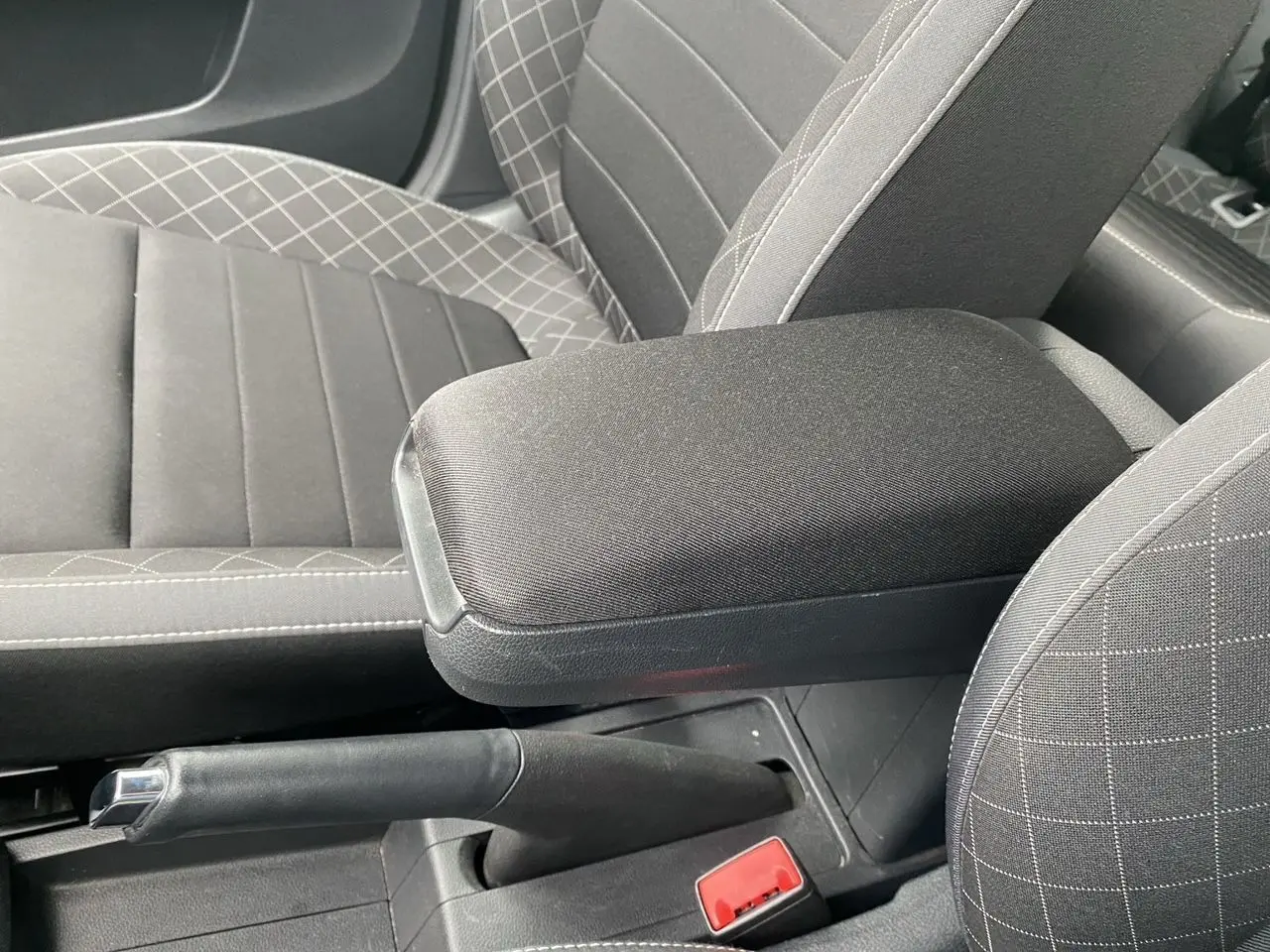 Gros plan sur l'accoudoir central et frein à main de la Skoda Fabia 2021, intérieur tissu gris à motifs croisés.