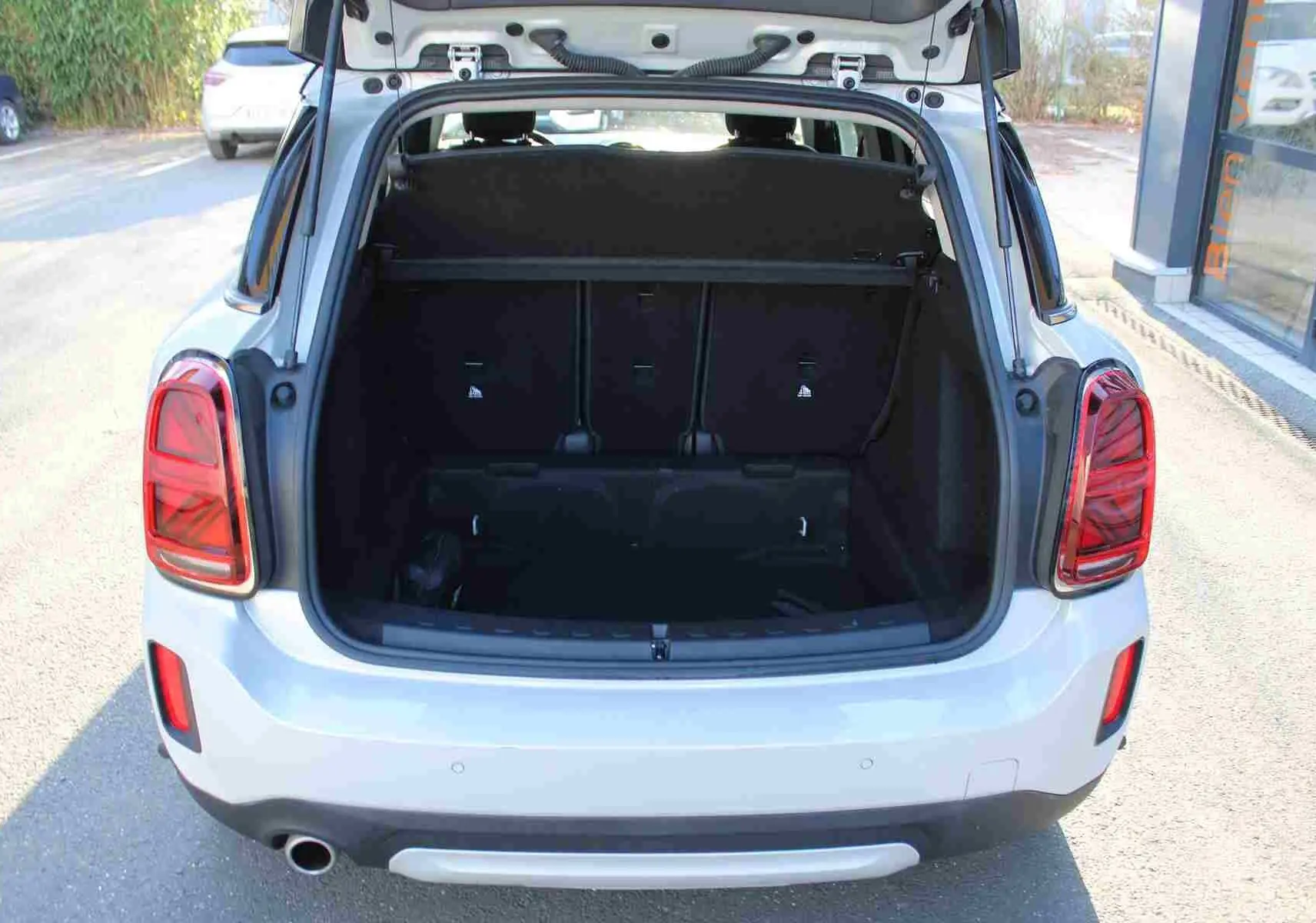Vue arrière ouverte du coffre d'une MINI Countryman gris perle métal avec toit noir, montrant l'espace de chargement.