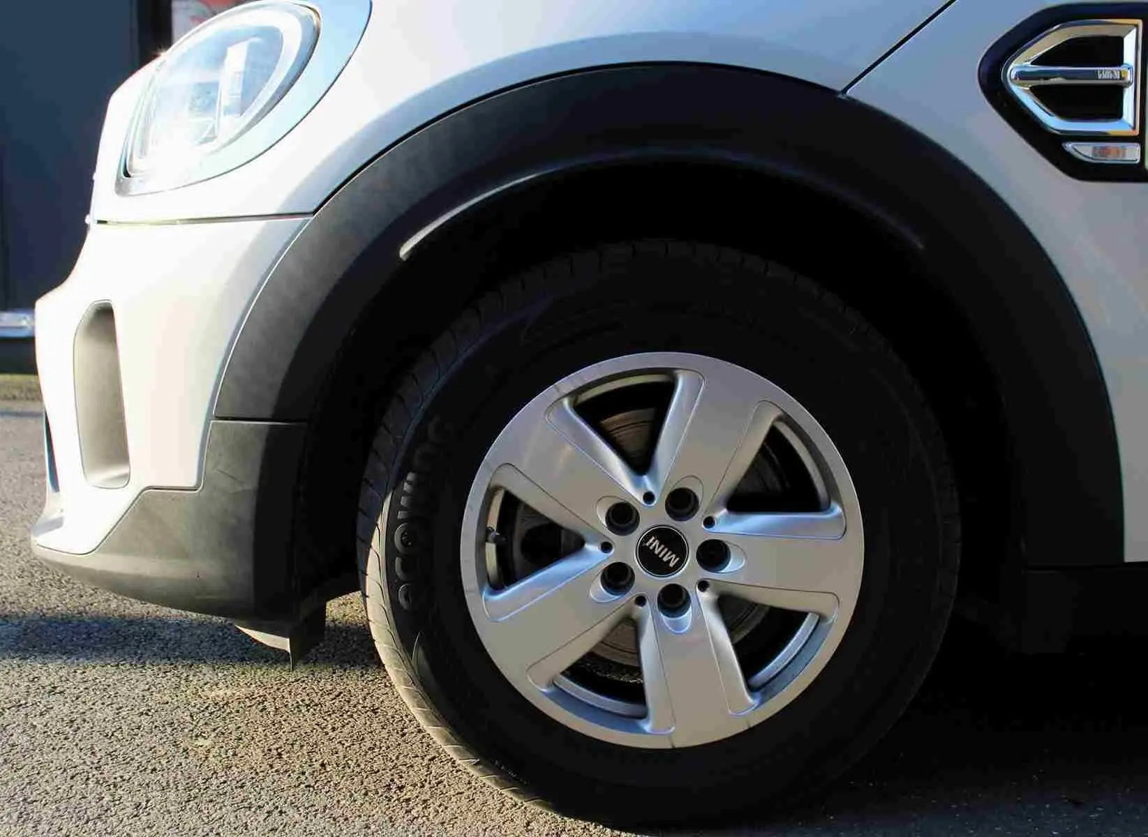 Gros plan sur la roue avant gauche d'une MINI Countryman gris perle métal avec jante alliage cinq branches.