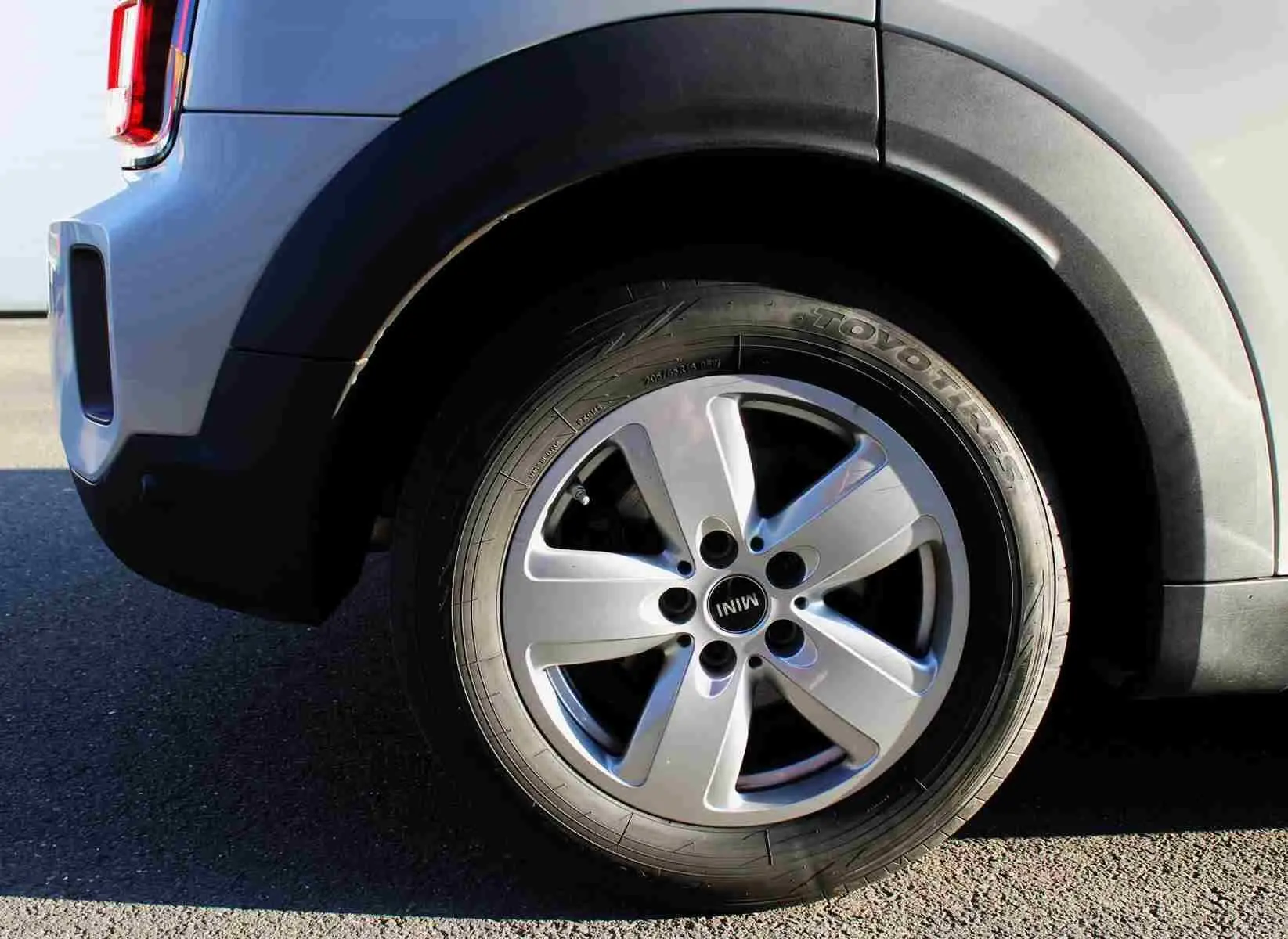 Gros plan sur la roue arrière droite d'une MINI Countryman gris perle métal avec jante alu cinq branches.