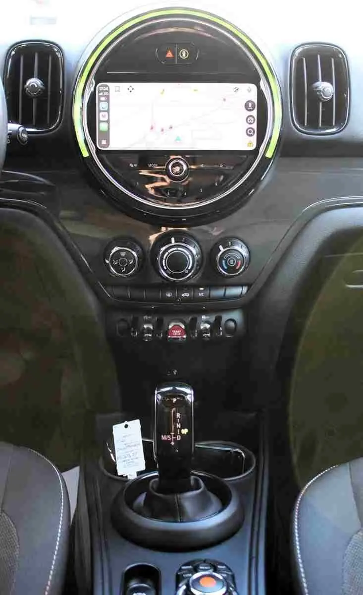 Vue centrée sur la console centrale du MINI Countryman 2020, écran tactile rond avec éclairage vert pâle et levier de vitesse automatique.