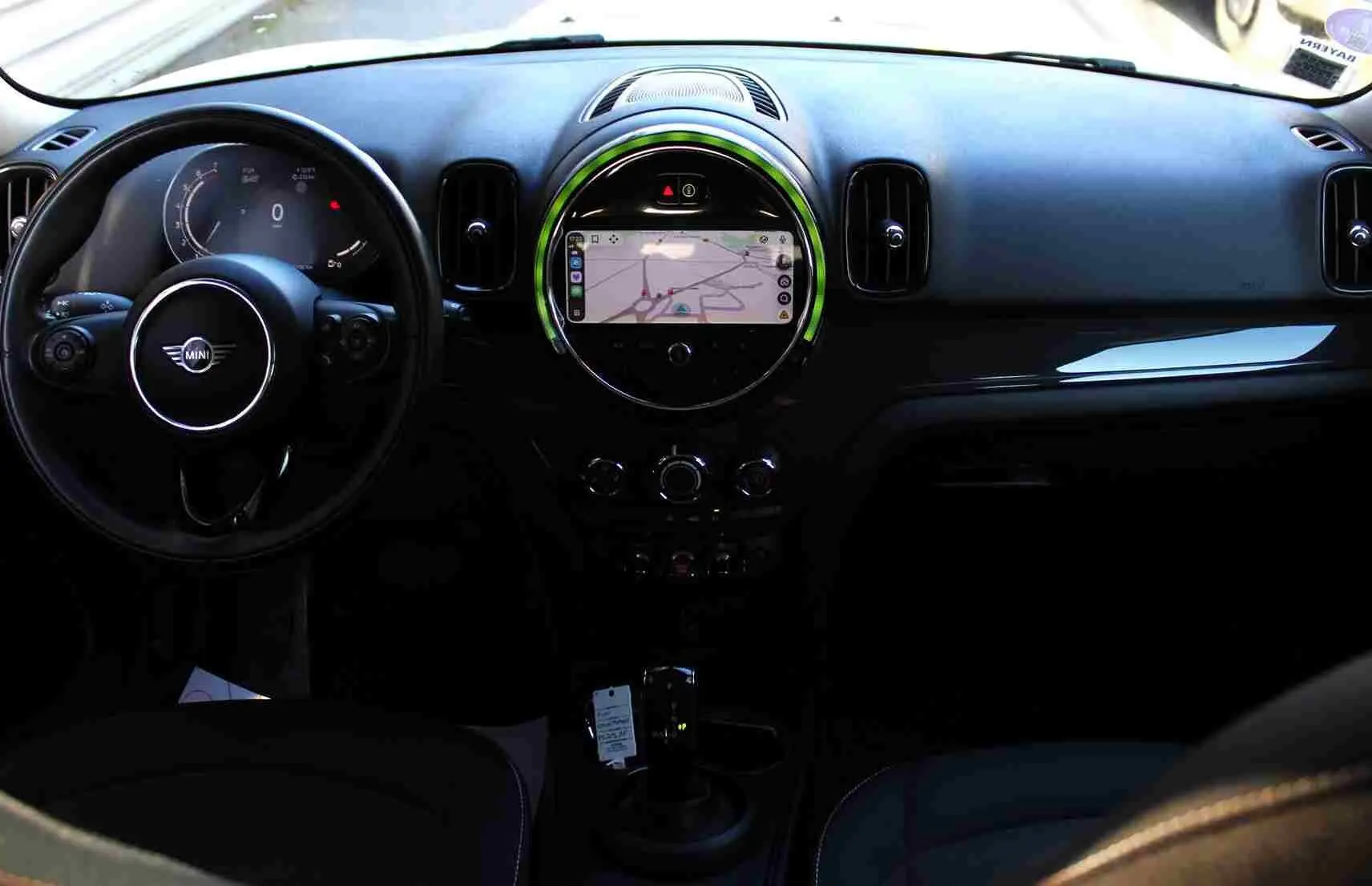 Tableau de bord et volant noir de MINI Countryman II avec écran central circulaire affichant la navigation GPS.