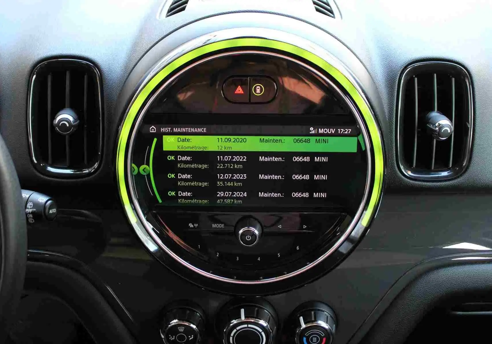 Vue rapprochée du tableau de bord noir du MINI Countryman 2020 avec écran central rond affichant l'historique de maintenance.