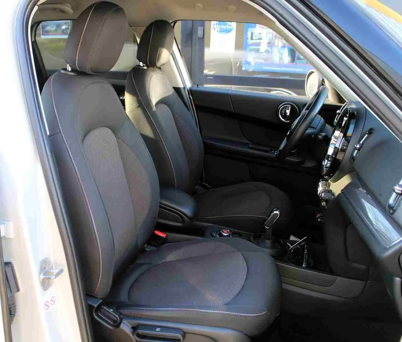 Vue intérieure côté conducteur du MINI Countryman gris perle métal, sièges tissu noir avec surpiqûres contrastées.