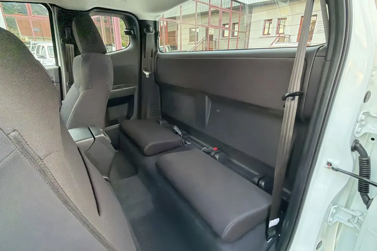 Vue intérieure côté droit du pick-up Isuzu D-MAX Splash White 2026, montrant les sièges arrière rabattus en tissu noir.