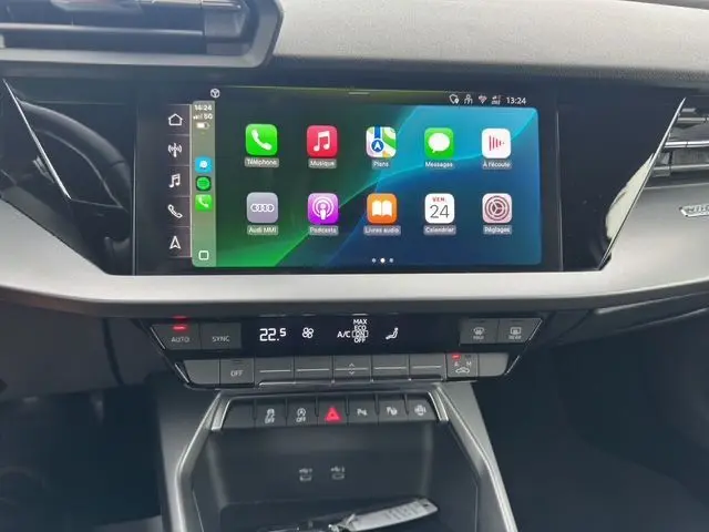 Vue rapprochée de l'écran tactile central et de la console de l'Audi A3 Sportback blanche Arkona 2024 avec interface Apple CarPlay.