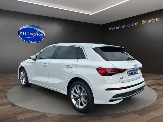 Audi A3 Sportback blanc Arkona vue 3/4 arrière droit en intérieur, avec jantes alliage et feux LED distinctifs.