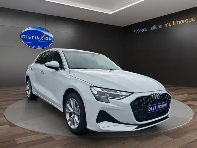 Audi A3 Sportback blanc Arkona vue 3/4 avant dans un showroom avec calandre noire et jantes alliage.