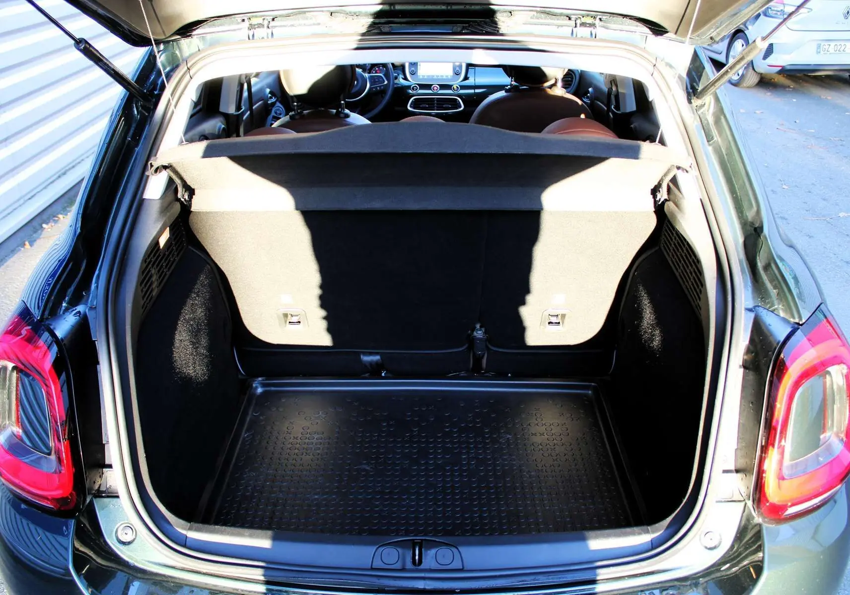 Coffre ouvert d'une FIAT 500X vert Toscane métal, vue arrière montrant l'espace de chargement et l'intérieur du véhicule.