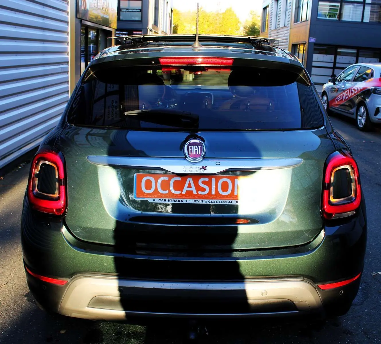 Vue arrière d'un FIAT 500X vert Toscane métallisé avec feux arrière LED et attelage visible en stationnement.