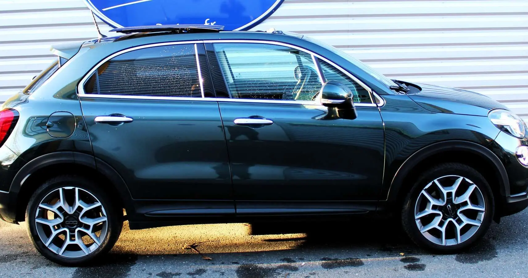 Profil côté gauche d'un FIAT 500X vert Toscane métal 2019, avec jantes alliage et poignées chromées visibles.