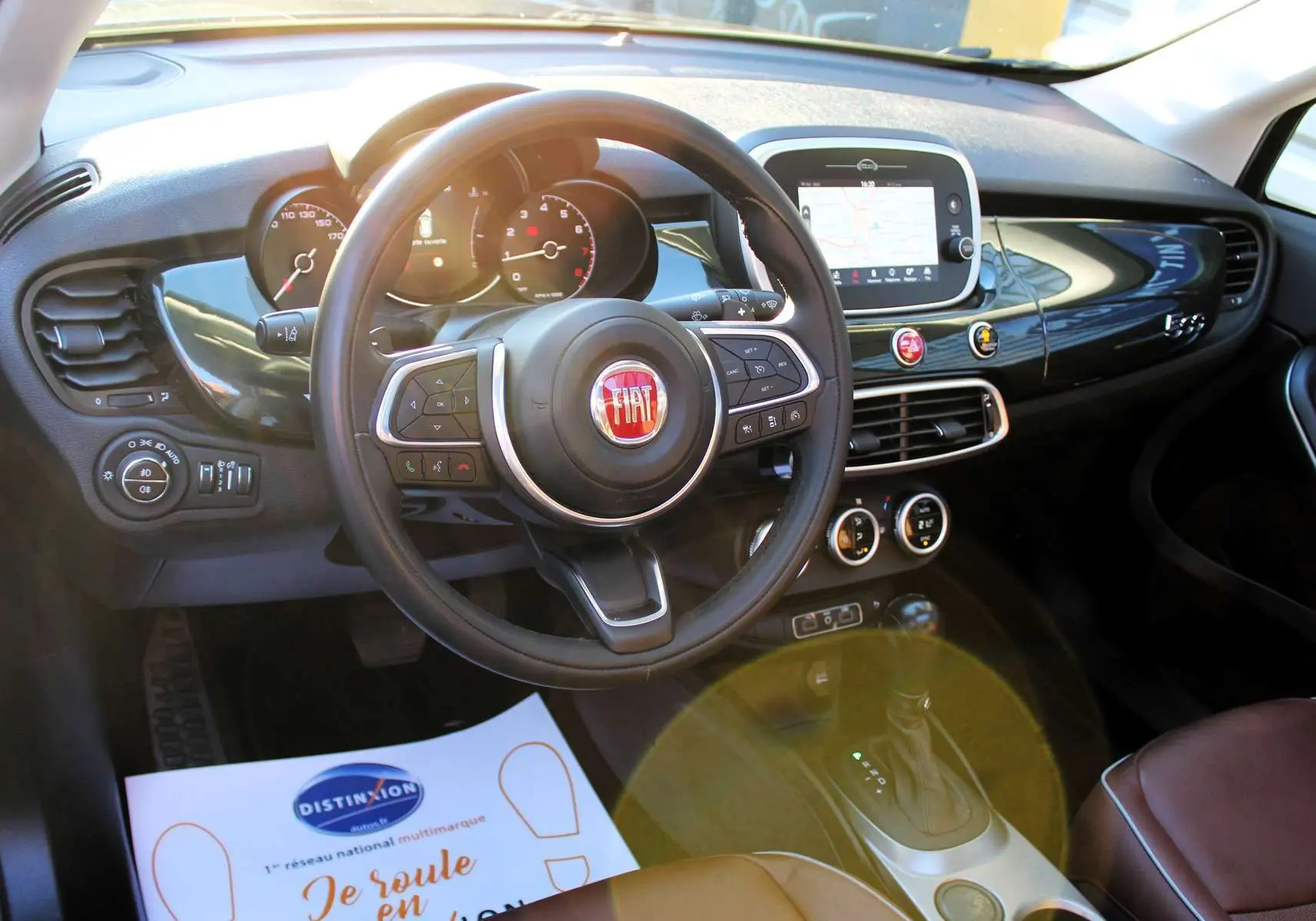 Intérieur de la Fiat 500X 2019 vu de face, tableau de bord noir brillant avec volant multifonction et écran tactile central.