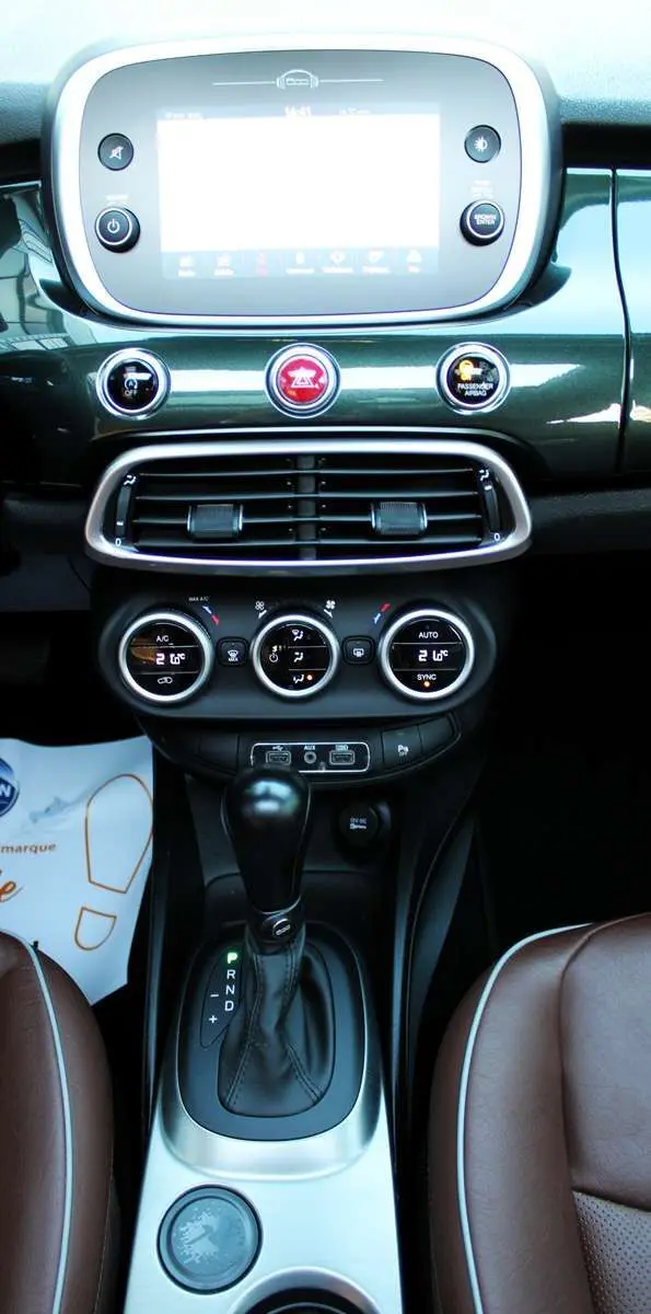 Vue rapprochée du tableau de bord vert Toscane métallisé de la Fiat 500X avec levier de boîte auto et sellerie marron.