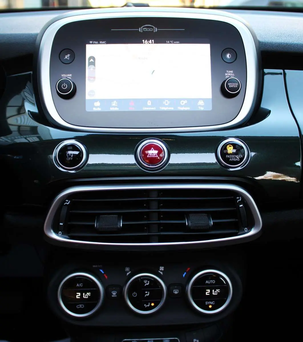 Tableau de bord de la Fiat 500X vert Toscane, avec écran tactile central et commandes de climatisation visibles.