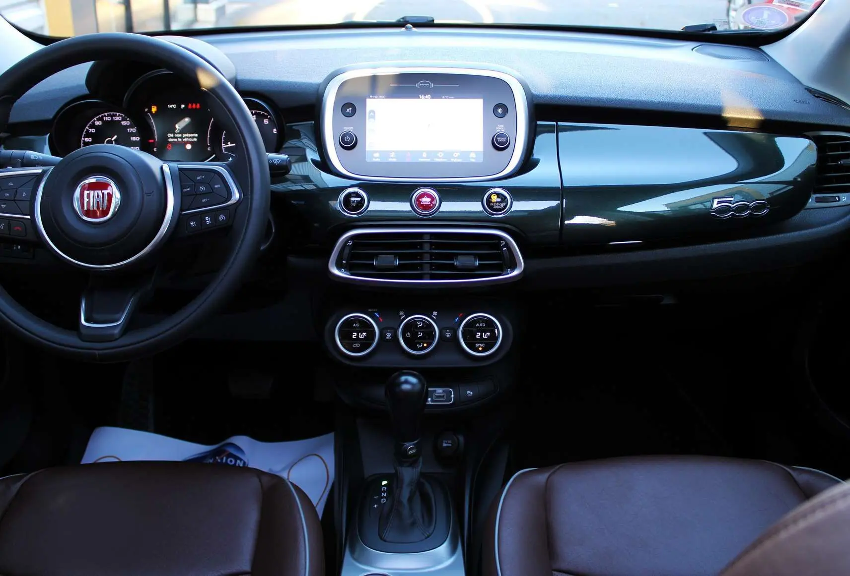 Intérieur du Fiat 500X 2019 avec tableau de bord vert Toscane métal, volant multifonction et sièges cuir marron.