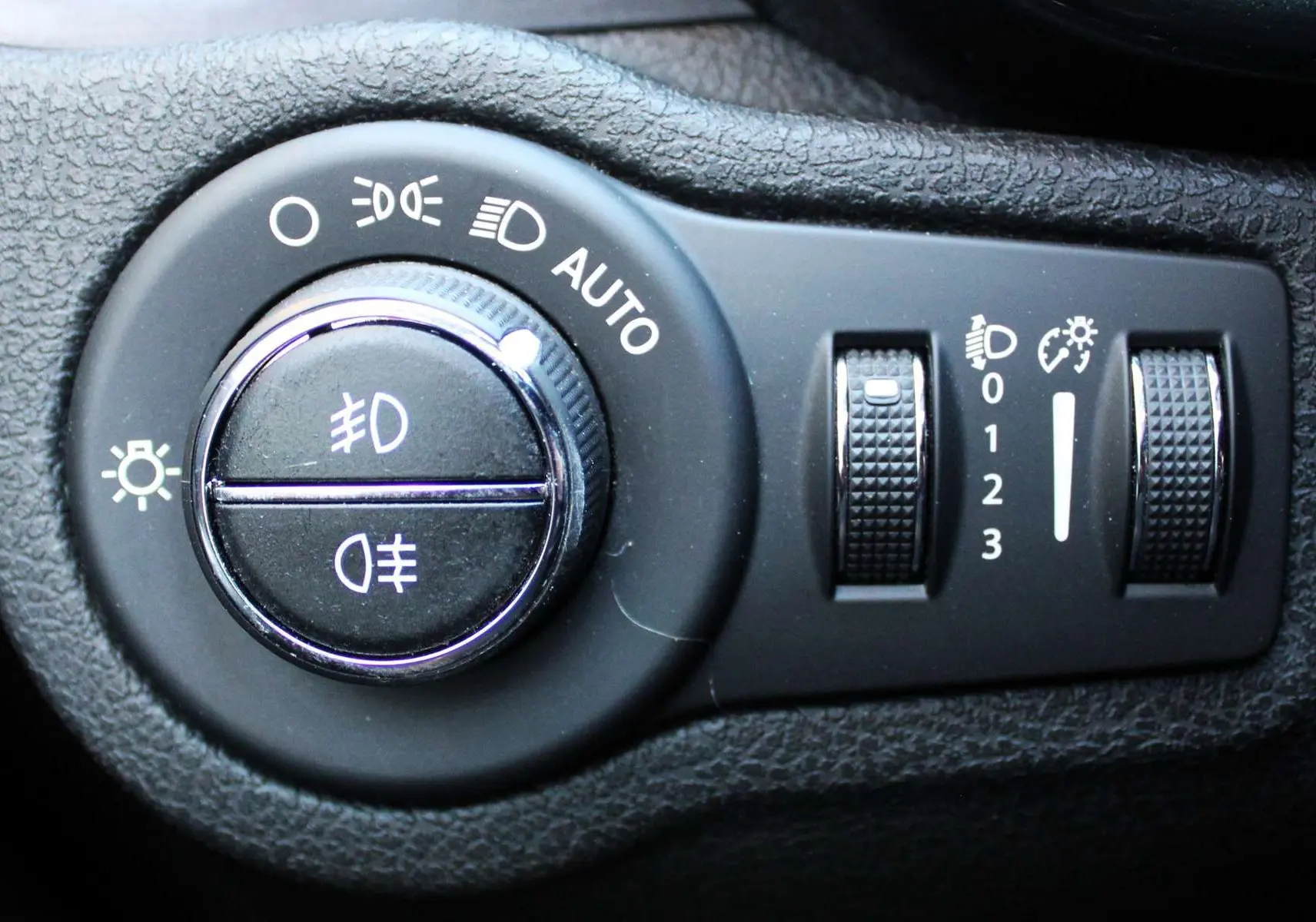 Gros plan sur les commandes d’éclairage et réglages du tableau de bord du Fiat 500X 2019, intérieur noir.