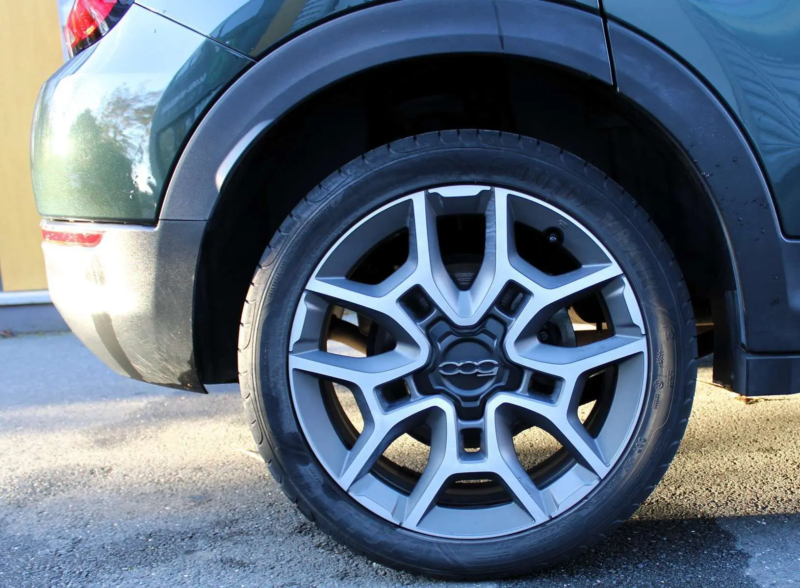 Gros plan sur la roue arrière droite d'une FIAT 500X vert Toscane métal avec jante alliage au design étoilé.