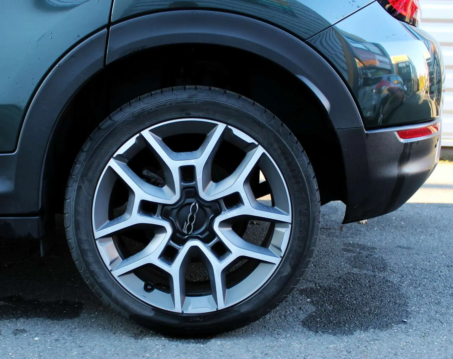 Gros plan sur la roue arrière droite d'une FIAT 500X vert Toscane métal, avec jante alliage bicolore et logo central 500.