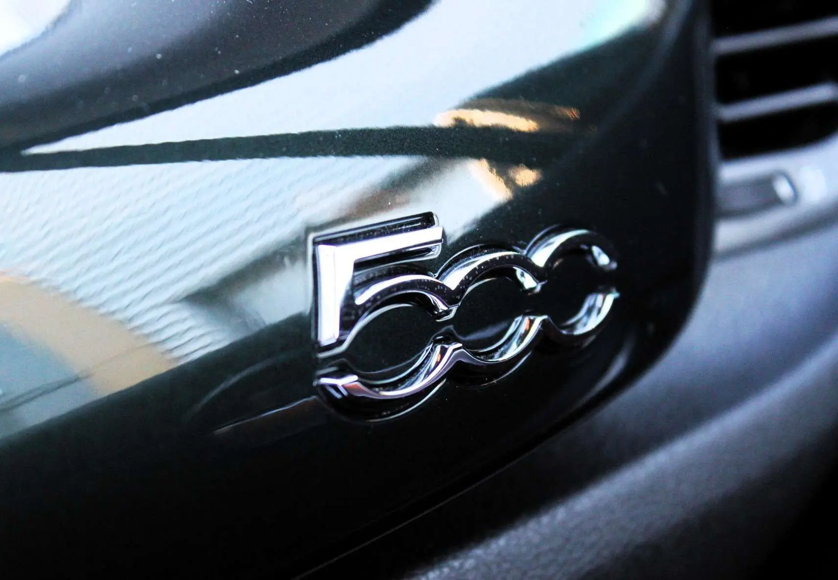 Gros plan sur le logo chromé 500 sur la planche de bord vert Toscane métallisé d'une Fiat 500X.
