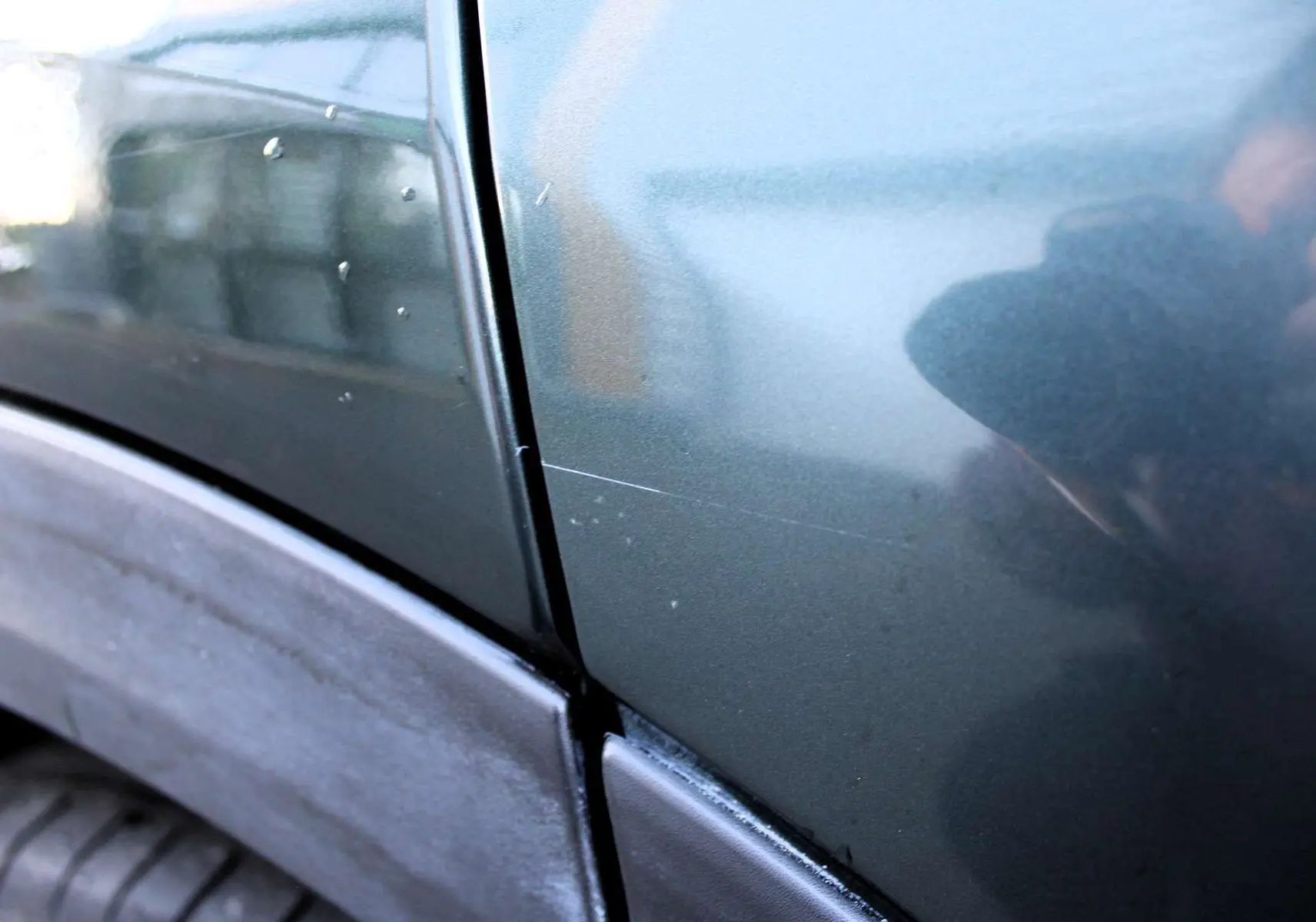 Gros plan sur la portière arrière droite vert Toscane métallisé du Fiat 500X avec rayure visible près du passage de roue.