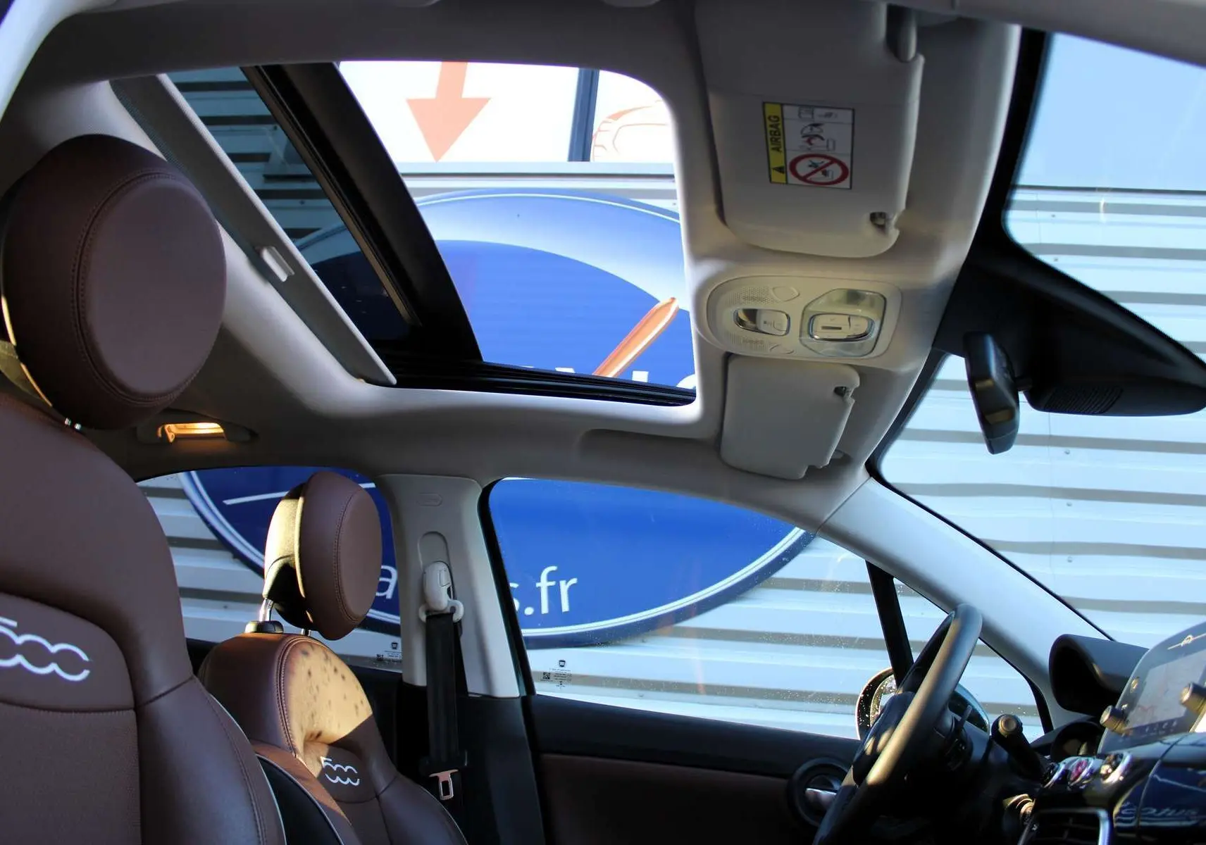 Intérieur de la FIAT 500X 2019 montrant les sièges marron avec logo 500 et toit ouvrant panoramique.