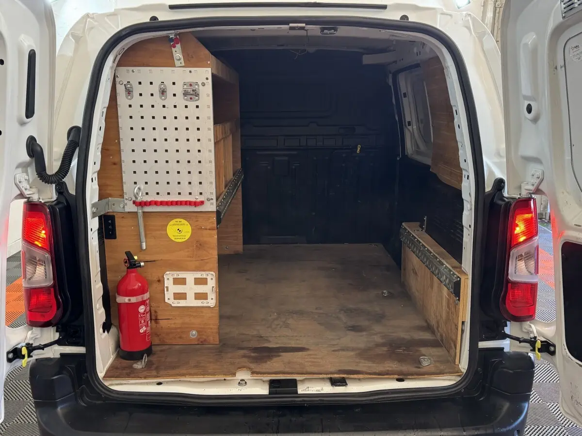 Vue arrière ouverte du Citroën Berlingo blanc 2020, montrant l’espace de chargement avec aménagements en bois et extincteur.