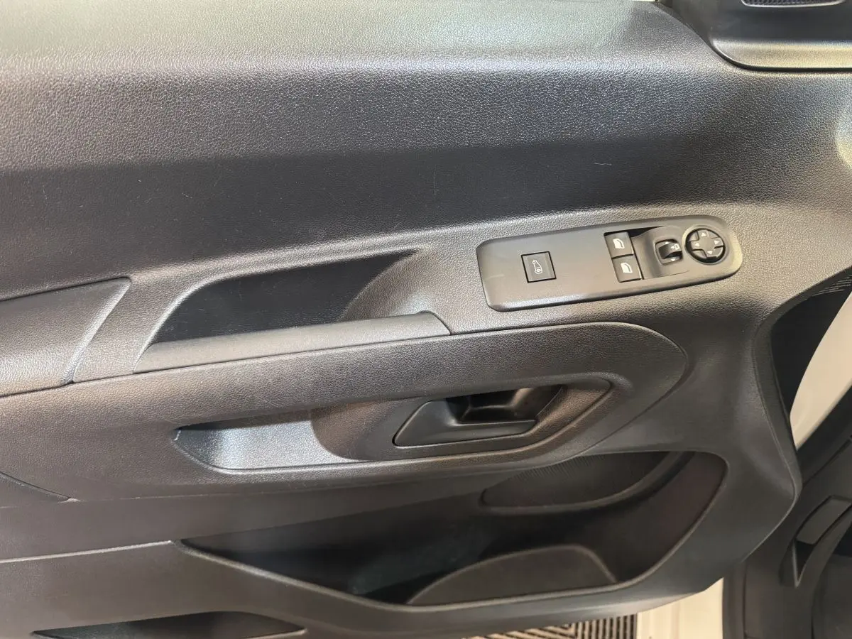 Gros plan sur la porte intérieure côté conducteur du Citroën Berlingo blanc, avec commandes électriques et poignée noire.